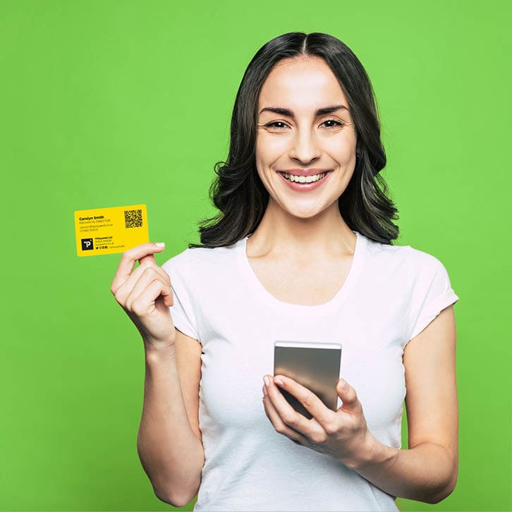 Bodacious girl with hazel eyes, slightly curled hair and such a brilliant smile in front of flamboyant orange background is holding her phone and a bank card 